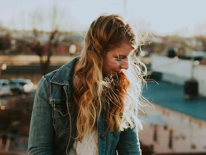 Junge Frau steht drau&szlig;en im Sonnenlicht